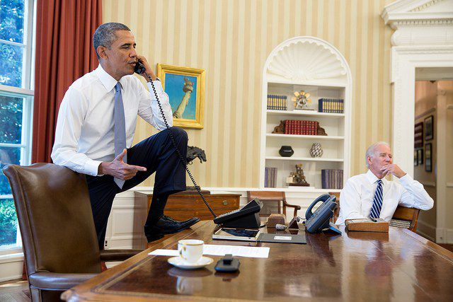 President Barack Obama talks on the phone in the Oval Office with Speaker of the House Boehner, Saturday, August 31, 2013. Vice President Joe Biden listens at right
